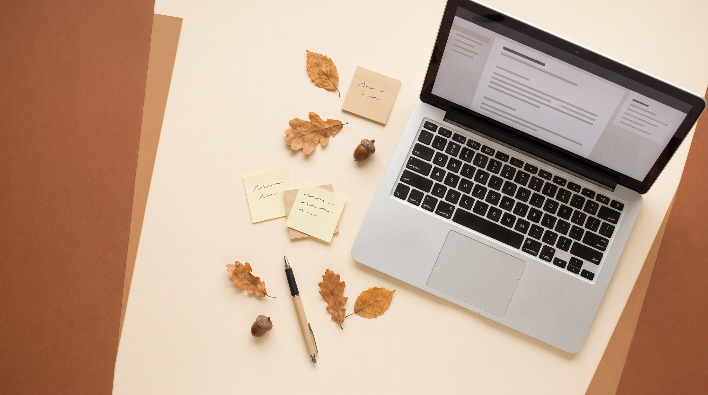 An overhead flat-lay of a tidy desk with a laptop displaying abstract placeholder lines, sticky note