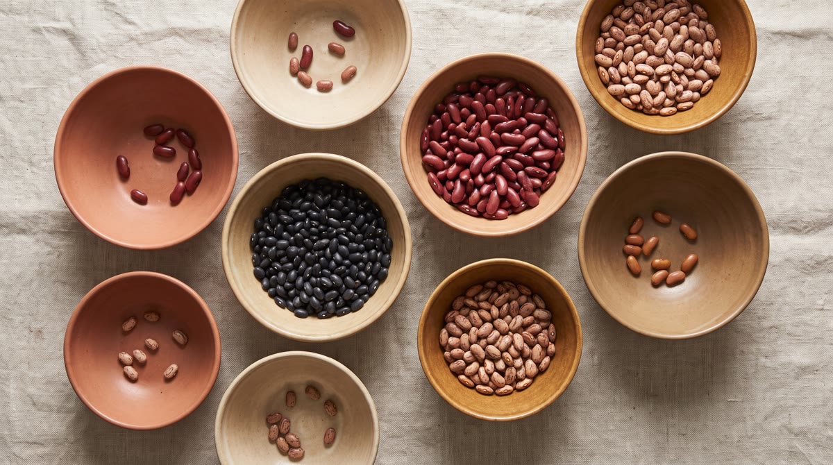 Overhead flat-lay of seven differently sized ceramic bowls in warm earth tones on a linen surface, s