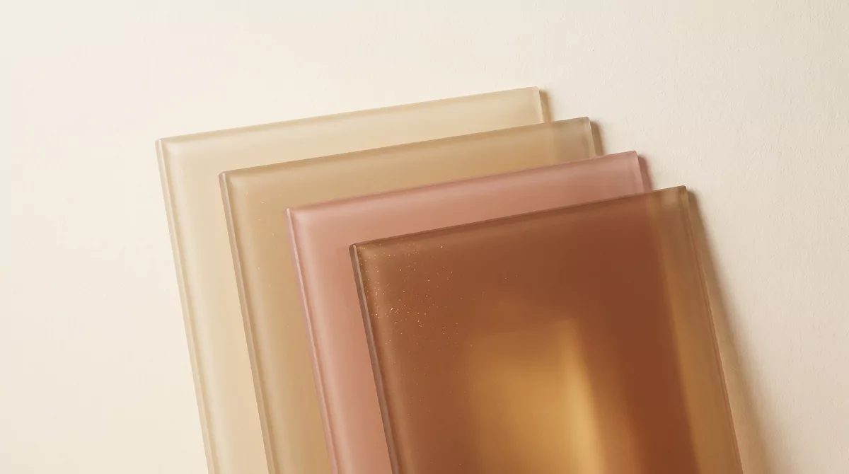 Five translucent panes of warm earth-toned glass stacked at slight angles against a soft cream backg