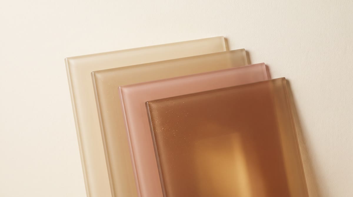 Five translucent panes of warm earth-toned glass stacked at slight angles against a soft cream backg
